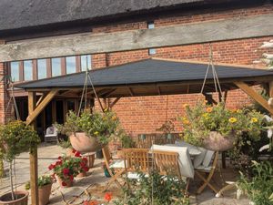 A timber framed, slate roofed open sided canopied seating area.