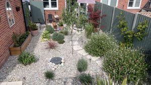A wooden fenced and gravel lined courtyard garden with Mediterranean style planting.